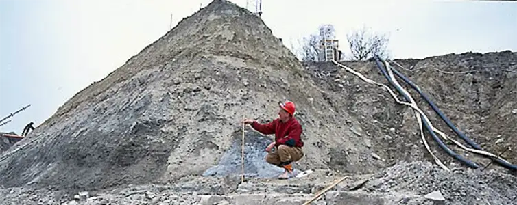 En mand måler noget fra en sandbunke